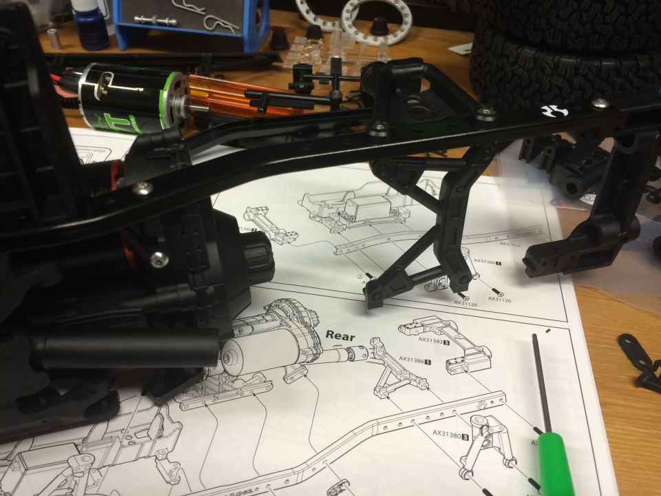 RC car chassis assembly with motor, suspension parts, and instructions.