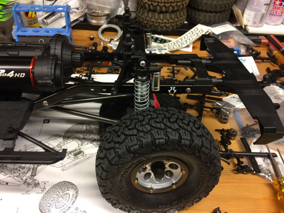 RC car chassis with large tire, motor, suspension, and parts.