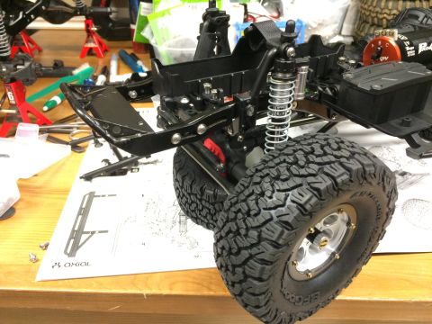 1989 Ford Bronco - RC car chassis assembly with detailed tires and suspension components visible on a workbench.