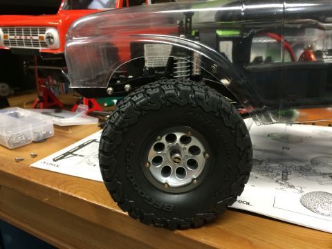 1989 Ford Bronco - A partially assembled RC car with a clear body sits on a workbench, with another vehicle body in the background.