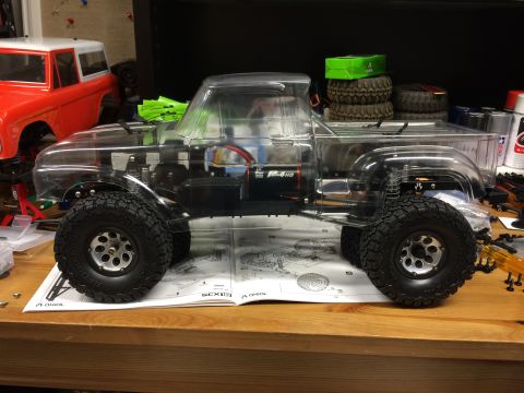 1989 Ford Bronco - RC truck with clear body sits on assembly instructions next to an orange RC Bronco body.