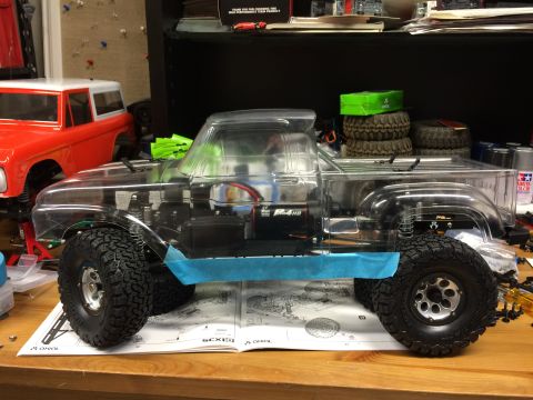 1989 Ford Bronco - A partially assembled RC truck sits on a workbench next to assembly instructions and another RC vehicle body.