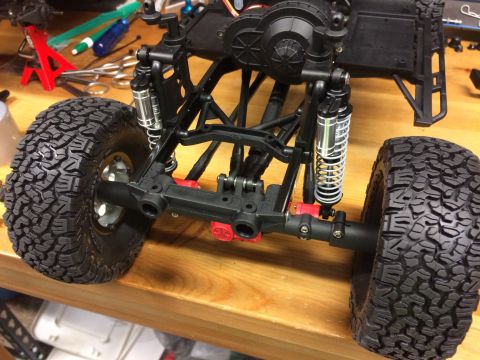1989 Ford Bronco - Close-up of an RC car chassis and tires on a wooden surface, with tools in the background.