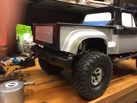 1989 Ford Bronco - RC truck model with large tires and a detailed rear end, on a workbench.