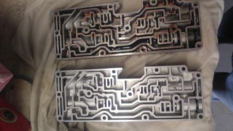 1991 Ford Bronco - A close-up shows two transmission valve bodies, one appearing used and the other clean.