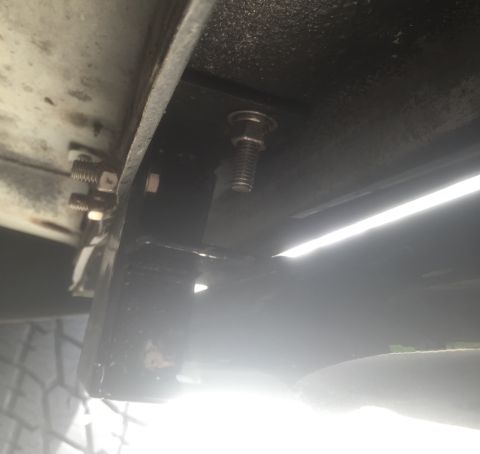 1995 Ford Bronco - Underside view of a vehicle's frame, showing mounting hardware and a tire.