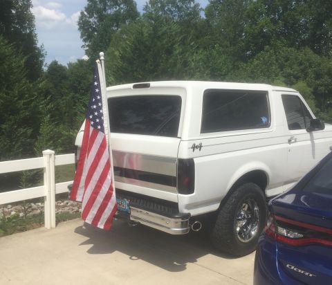 1995 Ford Bronco - A white 1992 Ford Bronco is parked next to a blue car, with an American flag attached to its rear.