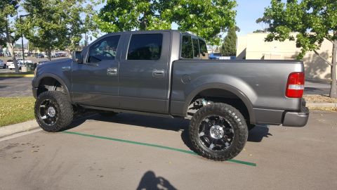 2005 Ford F-150 - This lifted 2005 Ford F-150 pickup truck features a dark gray exterior and custom black and chrome wheels.