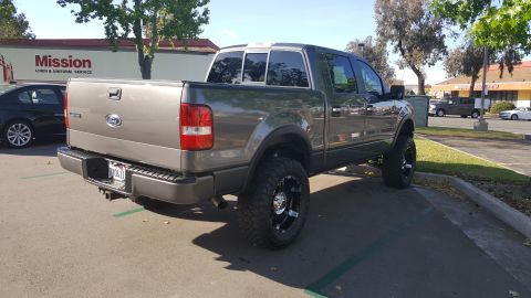 2005 Ford F-150 - Grey 2005 Ford F-150 pickup truck with custom wheels and lifted suspension is parked in a lot.