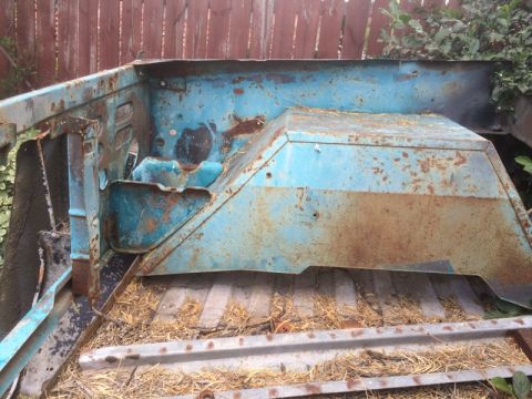 1979 Ford Bronco - This is a heavily rusted blue metal car part, likely from the interior or engine bay, with visible signs of decay.