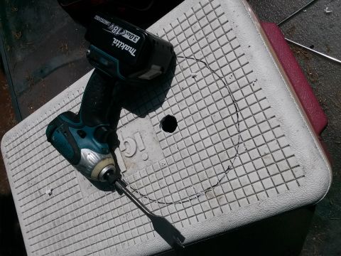 1996 Ford Bronco - A Makita drill and battery sit on a cooler lid, next to a circular cut marked by a pencil.