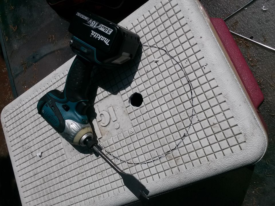 Drill and battery on a cooler lid with a cut circle