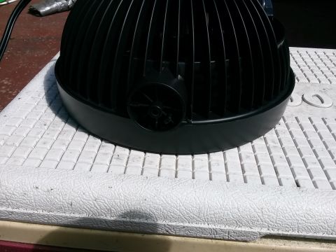 1996 Ford Bronco - A black fan assembly with a ribbed housing and a central circular vent is shown, resting on a textured surface.