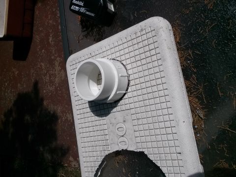 1996 Ford Bronco - A close-up view of a PVC pipe fitting installed on a textured surface, with a power tool battery nearby.