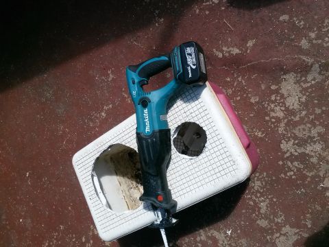 1996 Ford Bronco - A Makita reciprocating saw with an 18V battery rests on a white plastic surface, with a hole visible in the surface.
