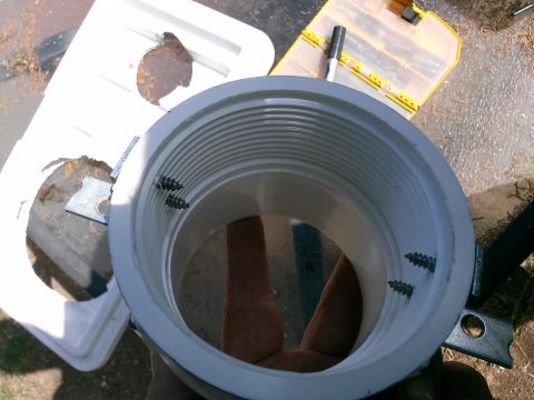 1996 Ford Bronco - A close-up view of a PVC pipe with screws, next to a white plastic container with debris.