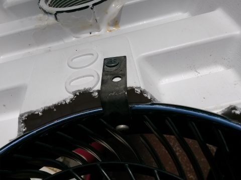 1996 Ford Bronco - Close-up of an air conditioner fan mounting bracket secured to a white plastic housing with a screw.