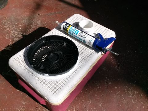 1996 Ford Bronco - Caulking gun, sealant, and fan motor are placed on a cooler, possibly for a repair or DIY project.