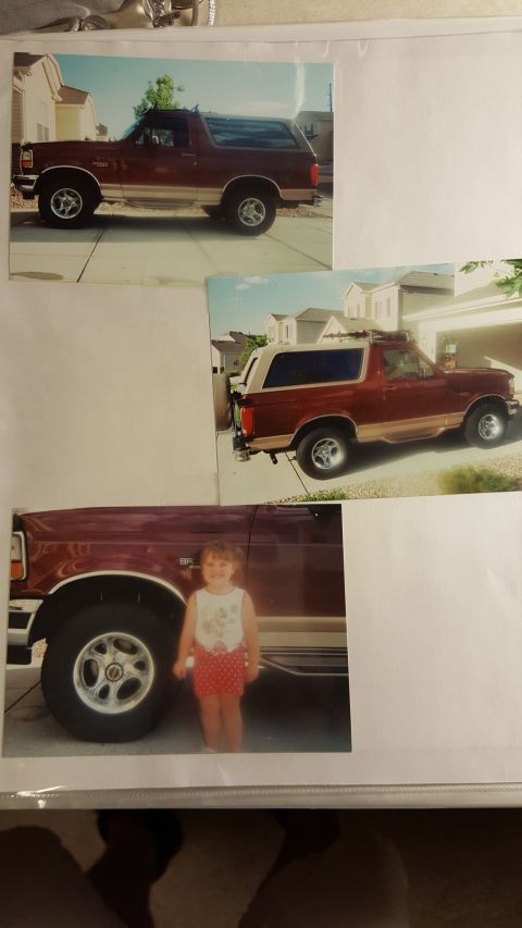 1996 Ford Bronco - A maroon Ford Bronco with tan trim is shown from the side, with a child standing by the front wheel.