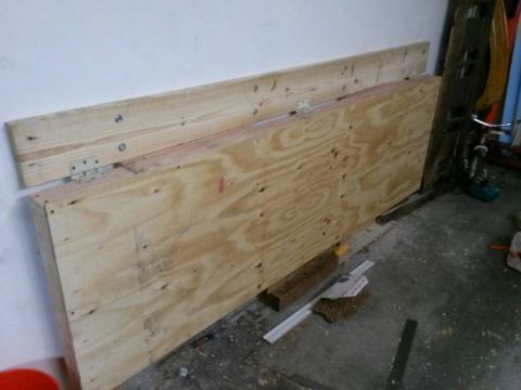1996 Ford Bronco - A workbench constructed from plywood and lumber is hinged to a wall in a garage setting.