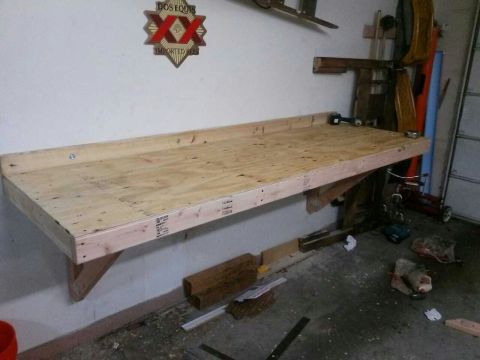1996 Ford Bronco - A wooden workbench is mounted to a garage wall, with a Dos Equis sign hanging above it.