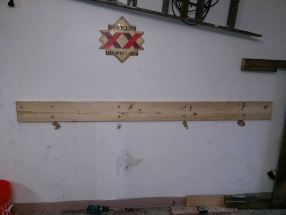 Wooden workbench mounted on a white wall with a Dos Equis sign above