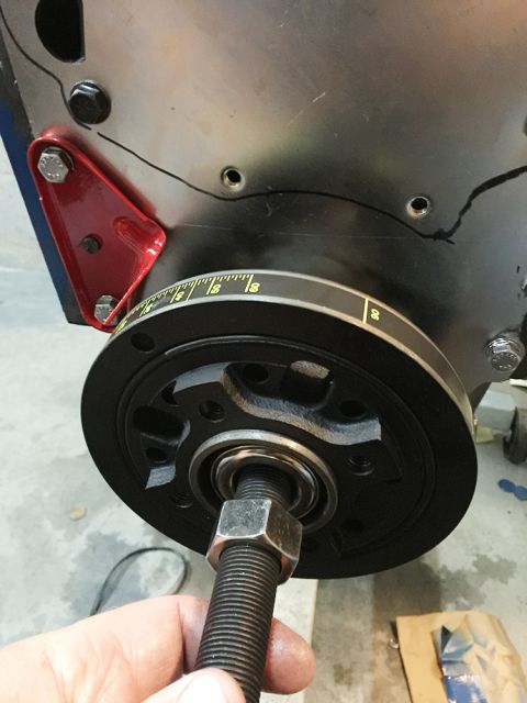 1978 Ford Bronco - Close-up of a crankshaft pulley with timing marks, showing a bolt being threaded into its center.