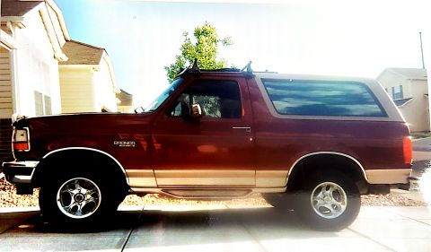 1996 Ford Bronco - Side view of a maroon 1996 Ford Bronco with tan two-tone paint and roof rack.