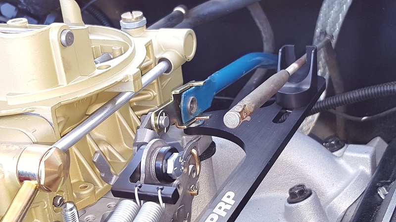 Gold carburetor with black and blue linkage assembly, showing a metal rod and springs