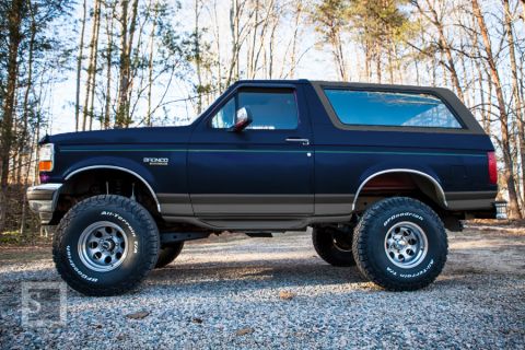 1995 Ford Bronco - This lifted 1995 Ford Bronco features a dark blue exterior with a grey accent stripe and BFGoodrich All-Terrain T/A tires.