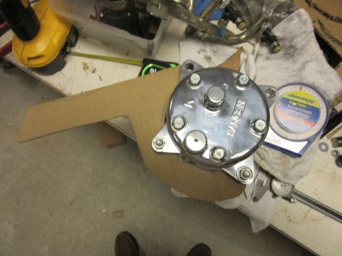 Sanden air conditioning compressor with cardboard template and measuring tools on a workbench