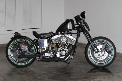 1975 Harley-Davidson FXRT Sport Glide - A custom black motorcycle with a prominent V-twin engine and whitewall tires is displayed indoors.