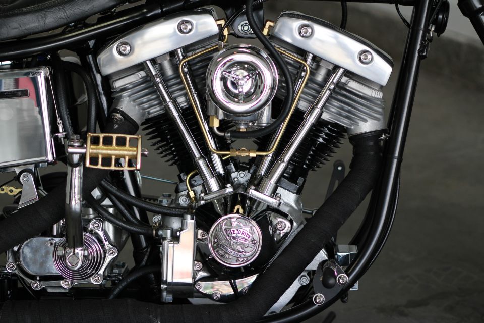 Close-up of a V-twin motorcycle engine with chrome accents and black exhaust wrap