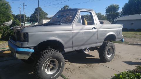 1991 Ford Bronco - This lifted Ford Bronco appears to be undergoing restoration, with its hood up and front bumper covered in tape.