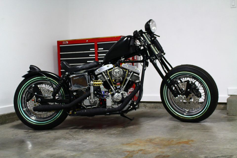 Side view of a black custom motorcycle with a V-twin engine and mint green tire accents