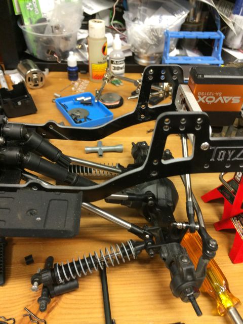 1989 Ford Bronco - RC car chassis parts and a servo are laid out on a workbench.