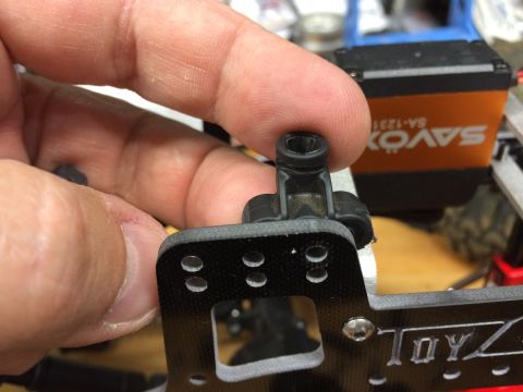 1989 Ford Bronco - Close-up of a hand holding a part from an RC car, with "TOYZ" visible on the chassis.