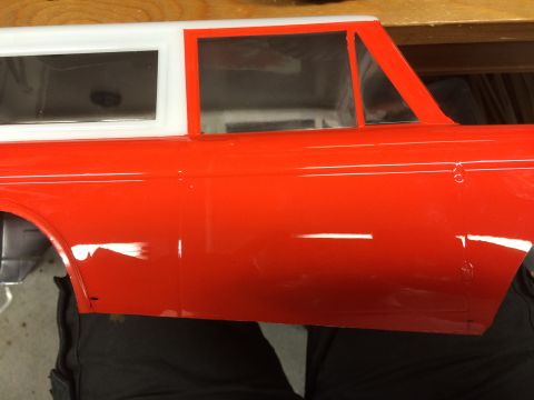 1989 Ford Bronco - Close-up of a red and white RC car body, showing the side panel and windows.