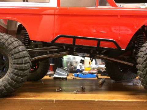 1989 Ford Bronco - RC car chassis and suspension components on a workbench, with parts and tools visible in the background.