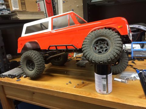 1989 Ford Bronco - An orange RC car body with a white top is shown on a workbench.