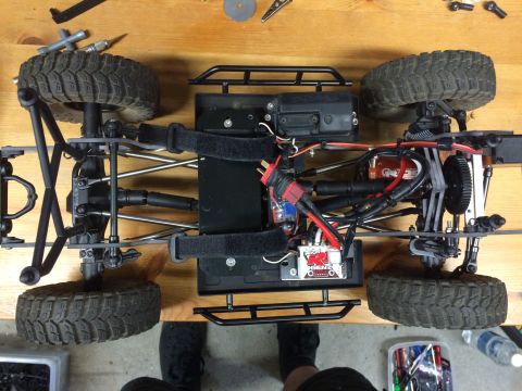 1989 Ford Bronco - The underside of a remote-controlled car chassis is shown, detailing its suspension, wiring, and tires.