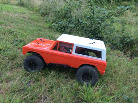 1989 Ford Bronco - An orange and white remote-controlled car sits on a patch of grass.