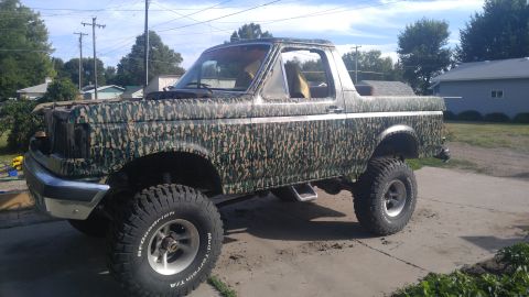 1991 Ford Bronco - This lifted Ford Bronco has a camouflage wrap and is parked in a driveway.