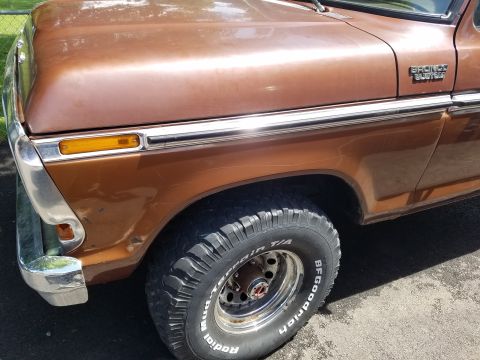 1979 Ford Bronco - Close-up of the front quarter panel and wheel of a brown Ford Bronco Custom.