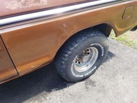 1979 Ford Bronco - The rear wheel well and side panel of a brown SUV are visible, showing a BFGoodrich tire.