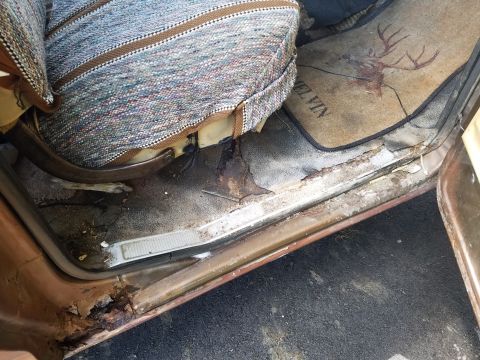 1979 Ford Bronco - The interior of this vehicle shows significant rust on the door sill and wear on the floor mat.