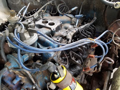 1979 Ford Bronco - Close-up view of a vehicle's engine components, including the distributor and ignition coil.