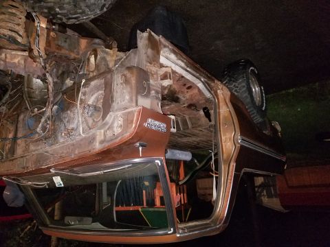 1979 Ford Bronco - The interior of a classic Ford Bronco is shown from a low angle, revealing extensive rust and exposed wiring. A spare tire is visible mount…