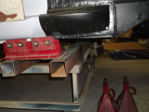1967 Ford Mustang - Car frame is elevated on jack stands and support beams in a workshop setting.