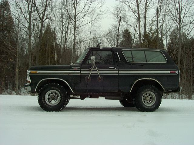 Black 1978 Ford Bronco in snow, side view, with chrome trim and aftermarket wheels